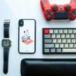 Flat Lay Photography of Dualshock 4 Beside Keyboard, Iphone X, and Digital Watch